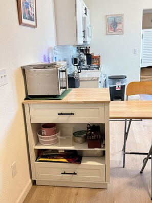 Eine Küchenzeile mit Toaster, Kaffeemaschine und Mülleimer.