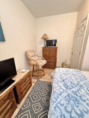 Ein Schlafzimmer mit einem Bett, einem Fernseher, einem Sessel, einem Schminktisch und einem Schrank.