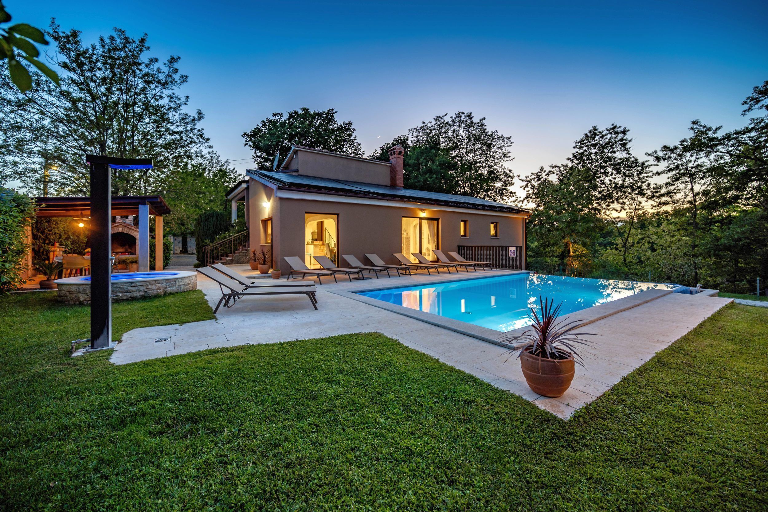 Ein modernes Haus mit Swimmingpool, Grillplatz und gepflegtem Rasen.