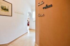 Ein Flur mit Kleiderhaken, einem gerahmten Bild an der Wand und einer Wand mit der Aufschrift 'Smile relax dream' in moderner Schrift.