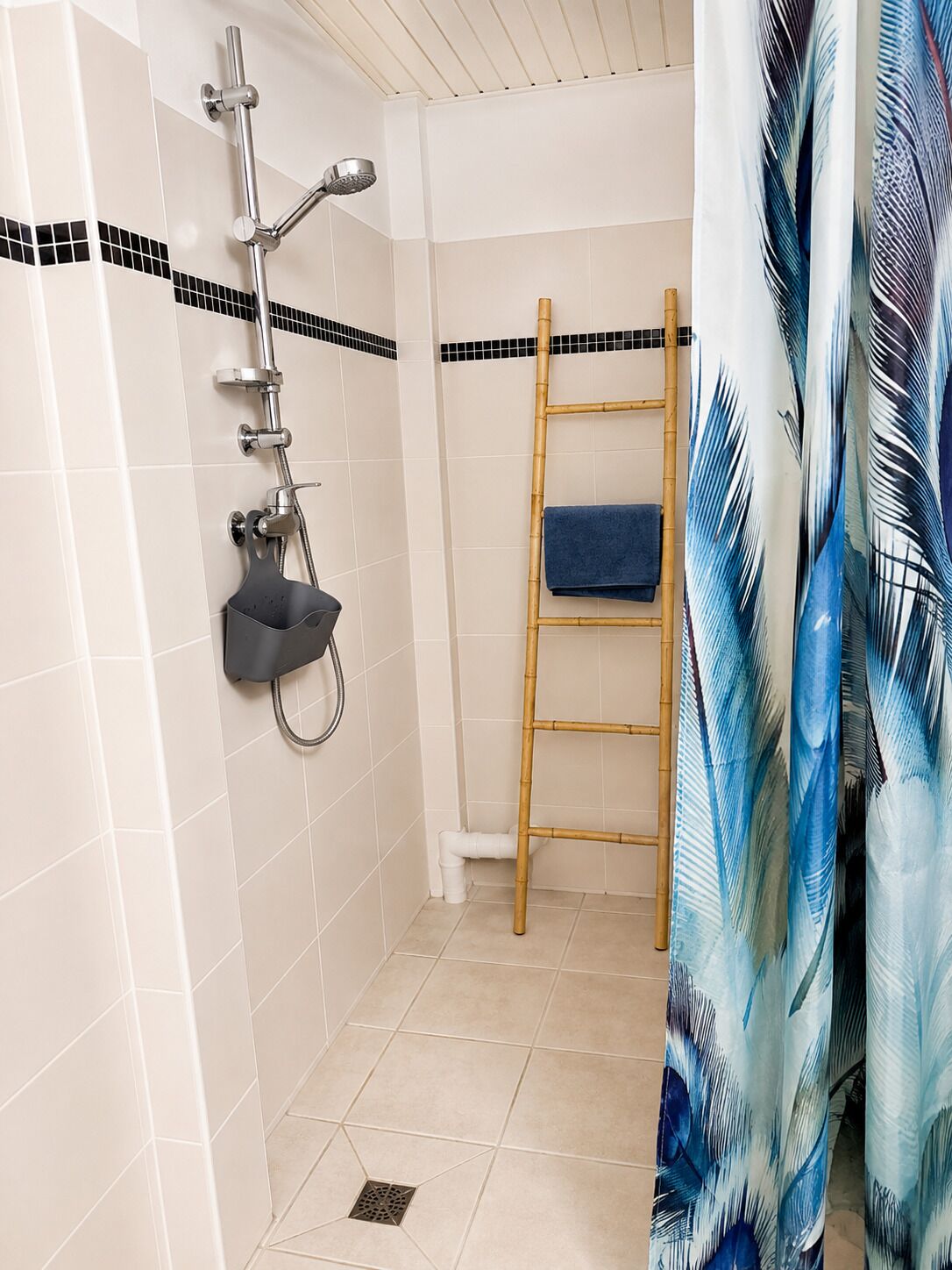 Ein Badezimmer mit Dusche, Handtuchhalter und einer Bambusleiter.