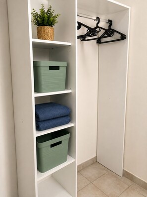 Un placard avec des étagères, une tringle et des bacs de rangement.