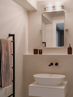 A bathroom with a white sink, a mirror, and a towel rack. - Fulham Residences Four (London)