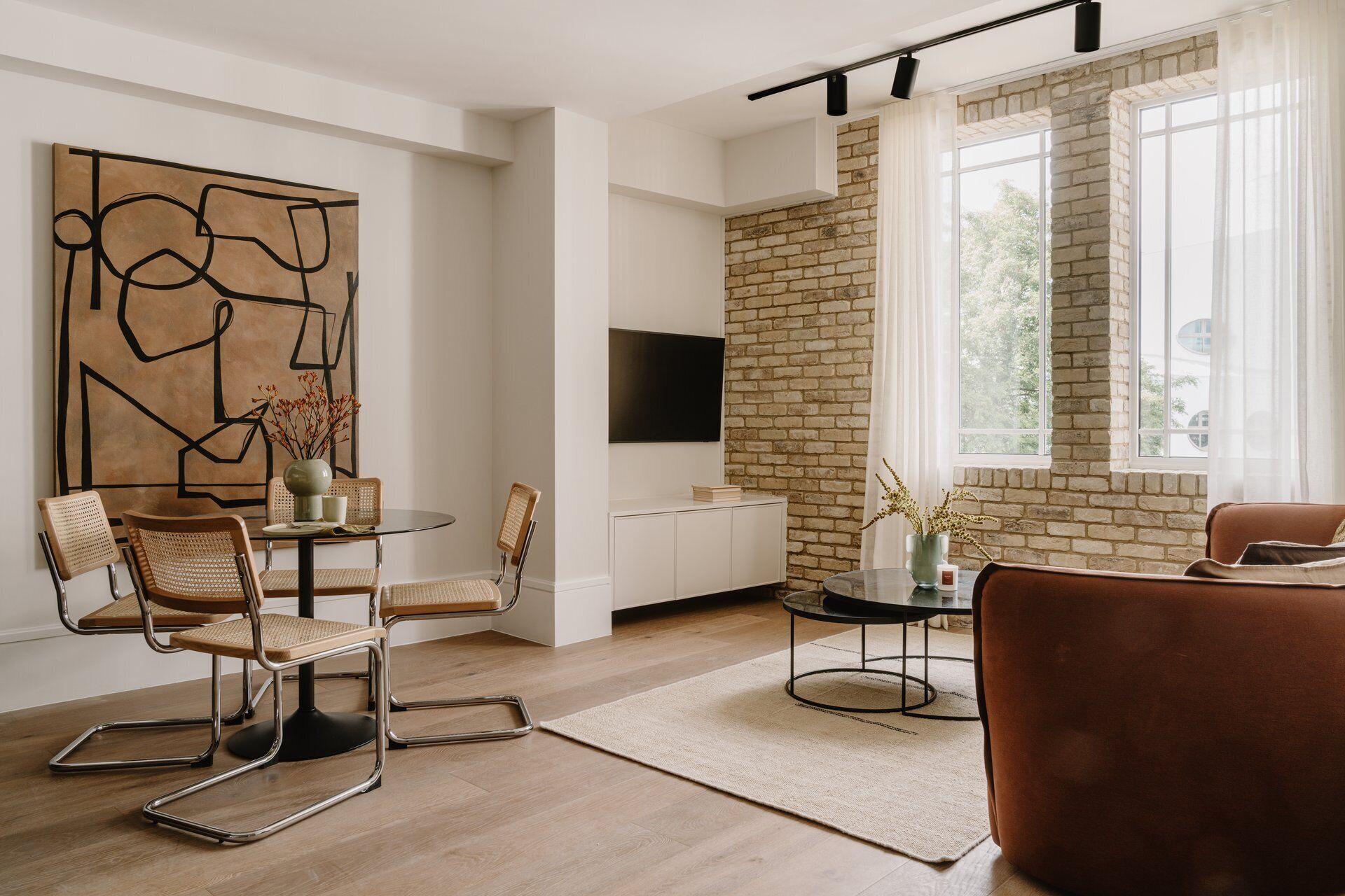 A modern living room with a brick wall, a round dining table, and a sofa.