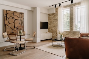 A modern living room with a brick wall, a round dining table, and a sofa. - Fulham Residences Four (London)