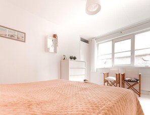 A bedroom with a large bed, a white wardrobe, a desk with a chair, and a window with a view. - Panoramic Dyke Villa With Whirlpool (Makkum)