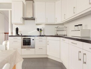 A modern kitchen with white cabinetry, stainless steel appliances, and a black countertop. - Panoramic Dyke Villa With Whirlpool (Makkum)