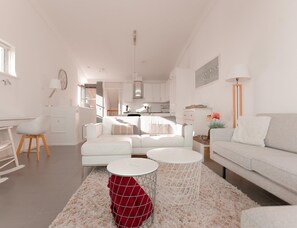 Un salon moderne avec un canapé, deux tables rondes et un plaid rouge posé sur un tapis moelleux.