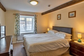 A bedroom with a bed, a nightstand, a dresser, a window with curtains, and a ceiling light. - Stylish City Apartment With Terrace (Ilfracombe)
