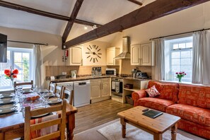 Una cocina acogedora con comedor, vigas de madera y un sofá rojo.