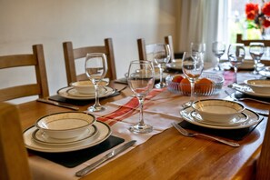 A dining table set with plates, glasses, and a bowl of fruit. - Stylish City Apartment With Terrace (Ilfracombe)