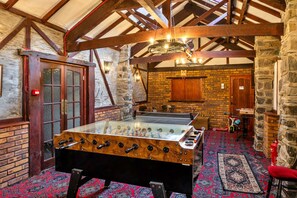 A room with a foosball table, a fireplace, and a stone wall. - Stylish City Apartment With Terrace (Ilfracombe)