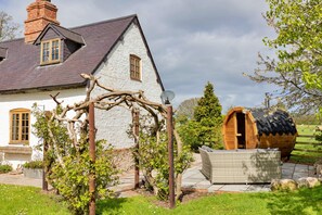 A white house with a grey roof, a wooden barrel structure, and a garden with a pergola. - Premium Country Lodge With Hot Tub (Saint Asaph)