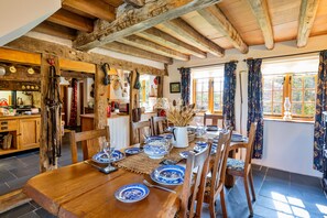 A rustic dining area with a wooden table set for four, surrounded by wooden chairs. - Premium Country Lodge With Hot Tub (Saint Asaph)