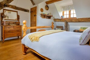 A bedroom with a wooden bed, a dresser, a mirror, and a window with a view. - Premium Country Lodge With Hot Tub (Saint Asaph)