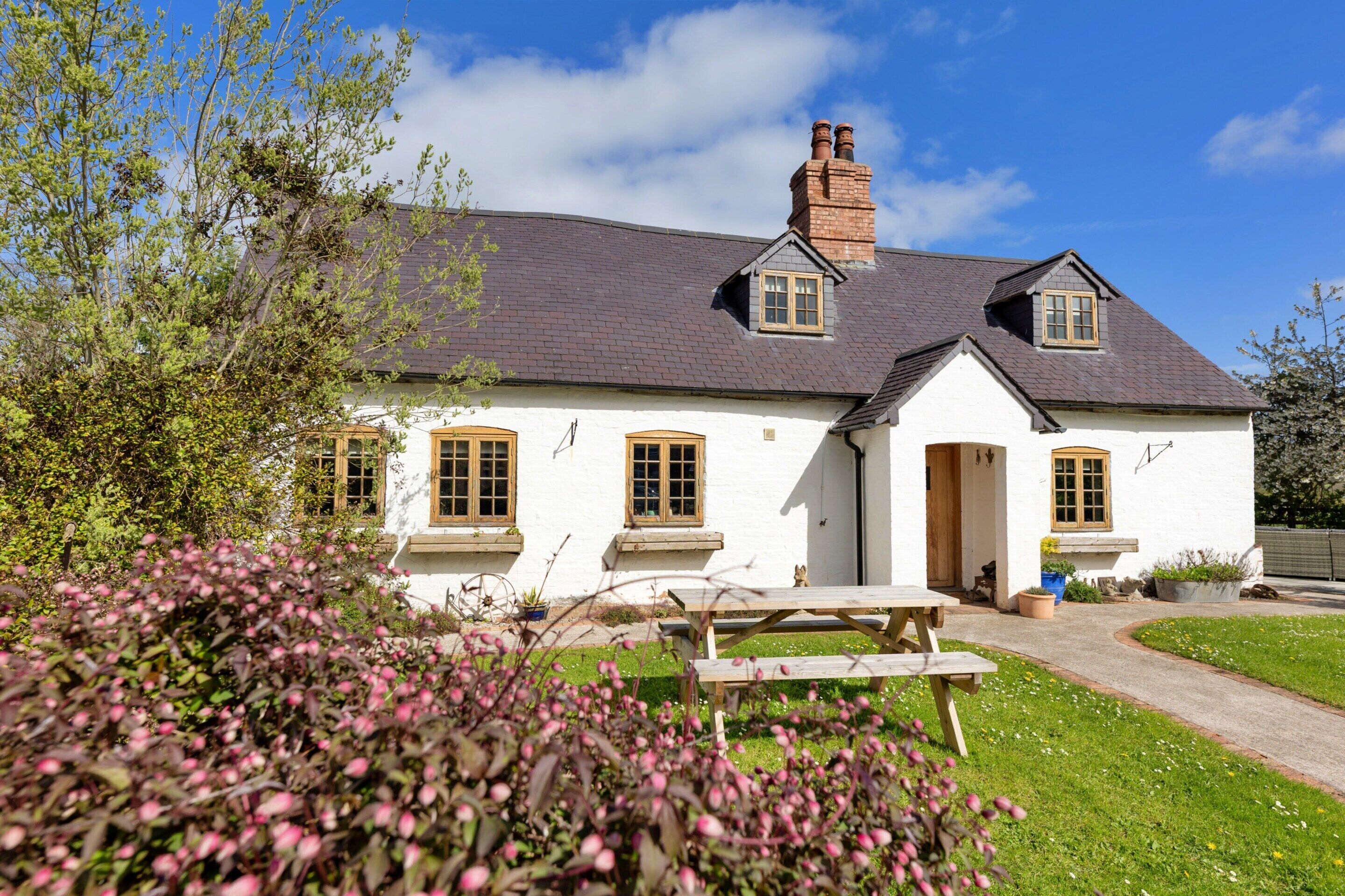 A white house with a grey roof, a chimney, and a small porch.