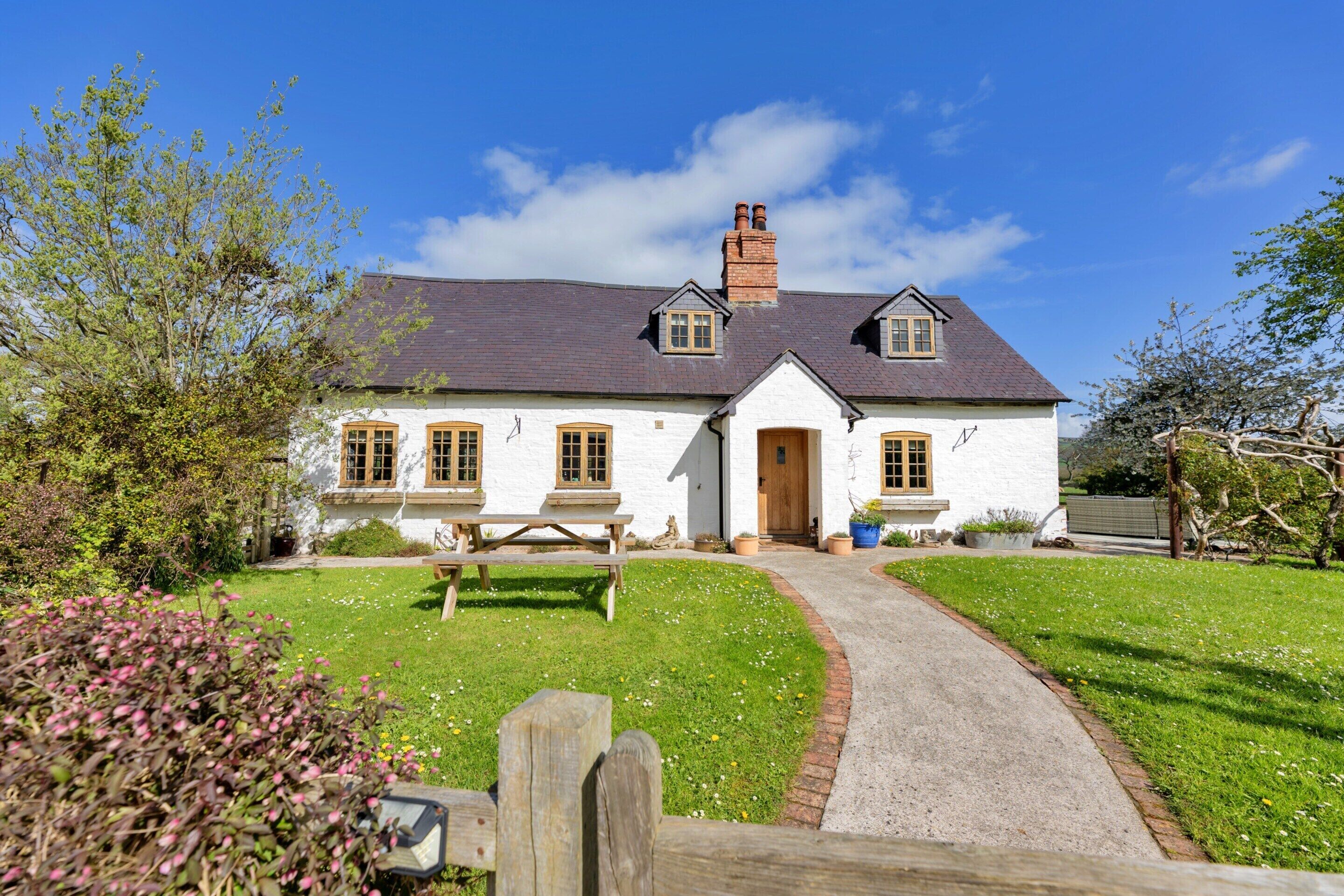 A white house with a dark roof, a wooden door, and a window with a wooden frame.