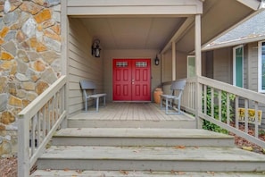 A front porch with a red door, stone wall, and a bench.