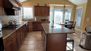 A spacious kitchen with a central island, wooden cabinets, and a large window providing natural light.