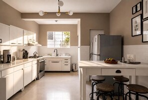 Eine moderne Küche mit weißen Schränken, einem Edelstahlkühlschrank und einer zentralen Kochinsel mit Sitzgelegenheiten.