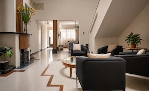 A modern living room with a fireplace, black sofas, a coffee table, and a view into another room. - Art Deco 6-Bedroom House in Condesa with a Rooftop (Ciudad de México)