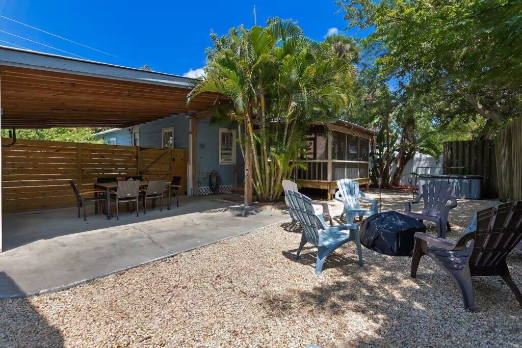 A covered outdoor area with seating, a grill, and a wooden fence.