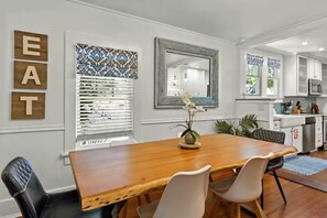 A dining area with a wooden table and chairs, a decorative mirror, and a wall-mounted sign spelling 'EAT'. - 3 BD/ 2 BA/ Saint Augustine (311 FB) (Saint Augustine)
