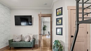 Une pièce avec un canapé vert, une porte en bois et un escalier.