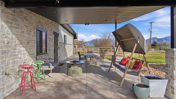 Un patio exterior con muros de piedra, un hogar para fogata, asientos y vistas a montañas.