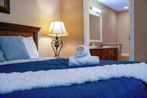 Ein Hotelzimmer mit einem ordentlich bezogenen Bett, einer Lampe, einem gefalteten Handtuch und einem Spiegel.