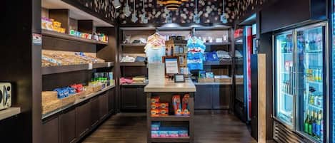 L’intérieur d’un magasin présente des étagères remplies de divers produits, un espace central dédié à la présentation des articles et une section réfrigérée située à droite.