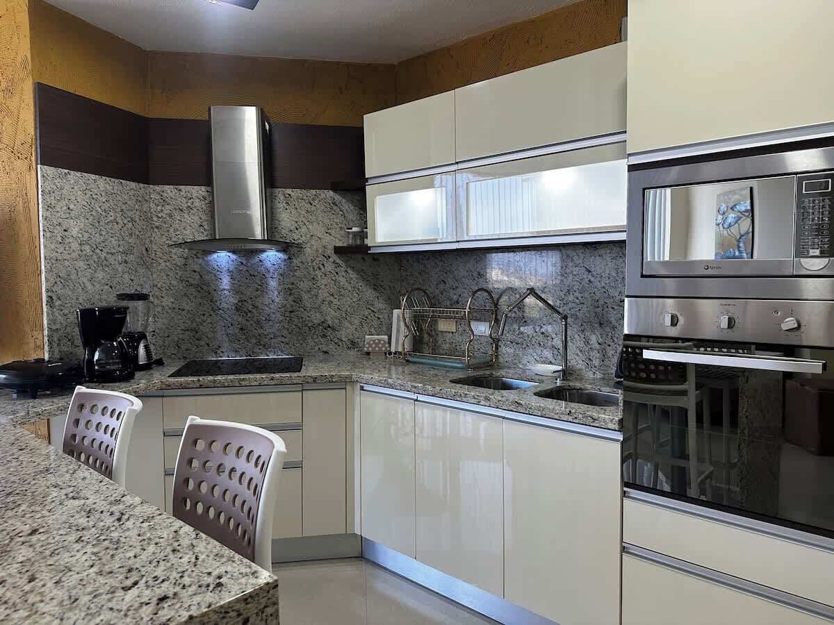 Una cocina moderna con encimeras de granito, electrodomésticos de acero inoxidable y armarios blancos.