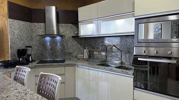 Una cocina moderna con encimeras de granito, electrodomésticos de acero inoxidable y armarios blancos.