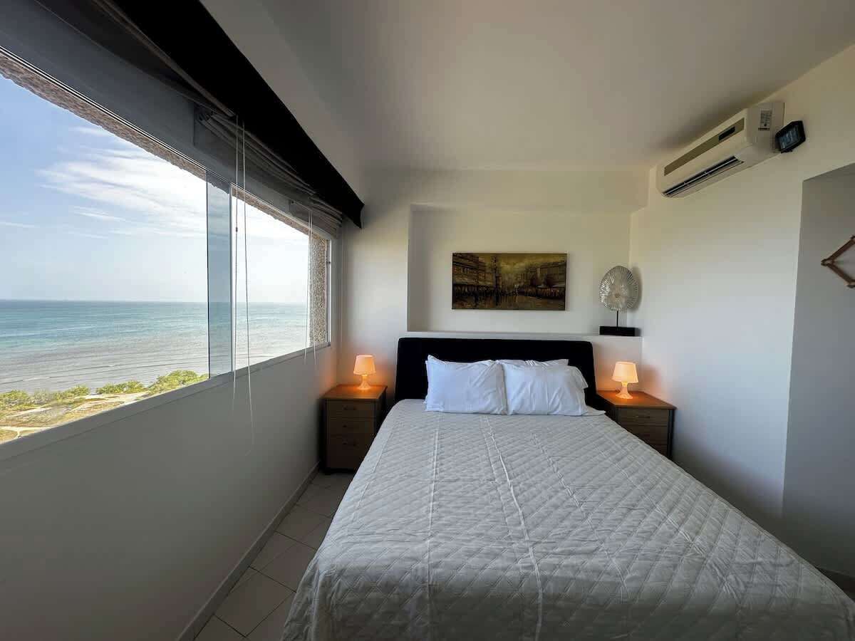 Una camera da letto con un letto grande, due comodini con lampade, una ventola a soffitto e un quadro appeso al muro.
