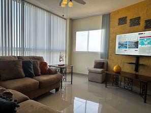 Una sala de estar moderna con un sofá, un sillón y un televisor de pantalla plana montado en la pared.