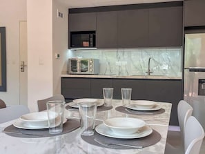 Uma cozinha moderna com bancada de mármore, micro-ondas embutido e eletrodomésticos de aço inoxidável.