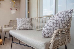 Ein rattangeflochtenes Sofa mit gemusterten Kissen in einem Raum mit einem großen Fenster.