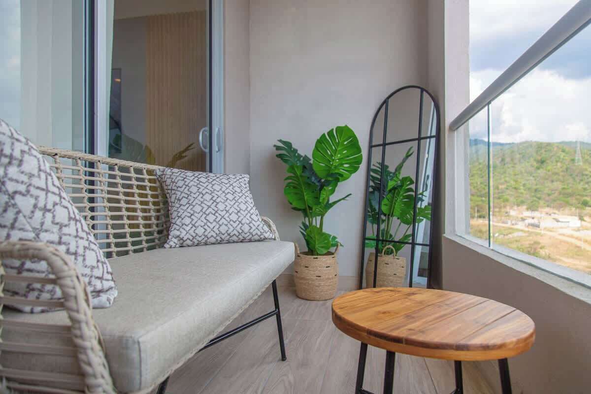 Un balcon avec un canapé, une petite table ronde et des plantes en pot.
