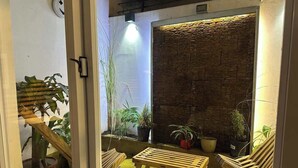 An indoor patio area with a stone wall, wooden furniture, and potted plants. - Apartment in Palermo Soho for 3 | Palermo Palms (Buenos Aires)