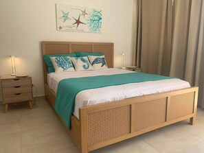 Una cama con cabecera de mimbre, colcha color turquesa y cojines decorativos.