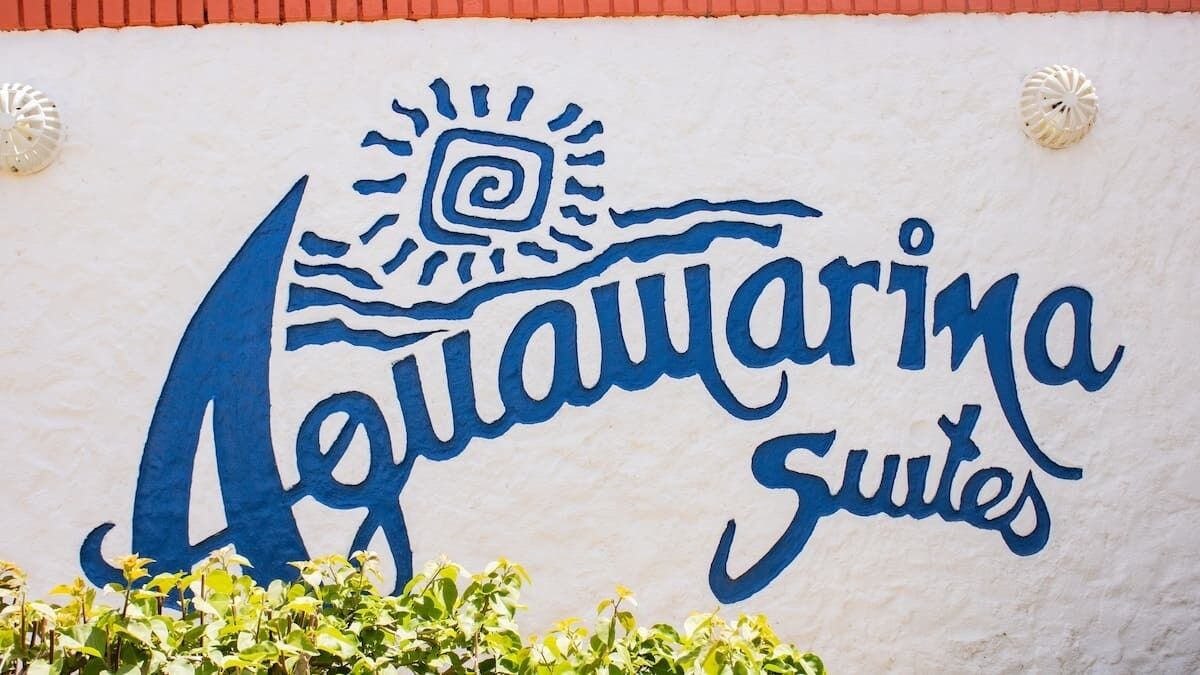 A sign for 'Aquamarina Suites' with a stylized sun and wave design.