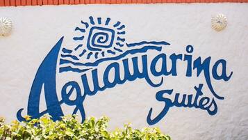 A sign for 'Aquamarina Suites' with a stylized sun and wave design.