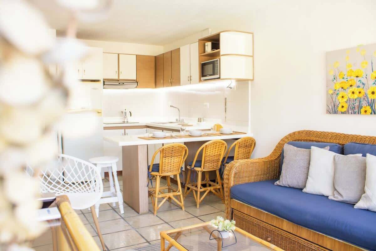 Een moderne keuken met een centraal kookeiland, eetstoelen en een bank met kussens.