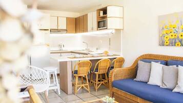 Een moderne keuken met een centraal kookeiland, eetstoelen en een bank met kussens.