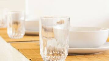 A clear glass on a bamboo mat with a white plate and another glass in the background.