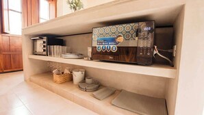 Een keuken met een magnetron op een plank, een broodrooster en divers keukengerei.