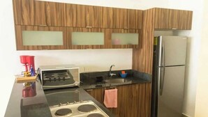 Een moderne keuken met houten kastjes, een roestvrijstalen koelkast, een gasfornuis en een zwart aanrecht.