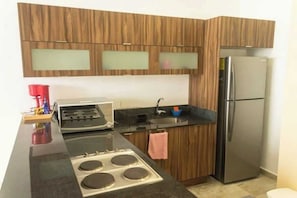A modern kitchen with wooden cabinets, a stainless steel refrigerator, a gas stove, and a black countertop. - Spacious and cozy apartment with garden (Merida)