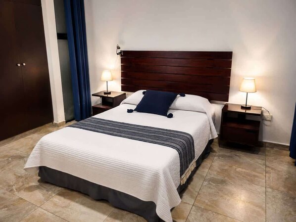 A hotel room with a large bed, two bedside tables, and a wooden headboard. - Spacious and cozy apartment with garden (Merida)