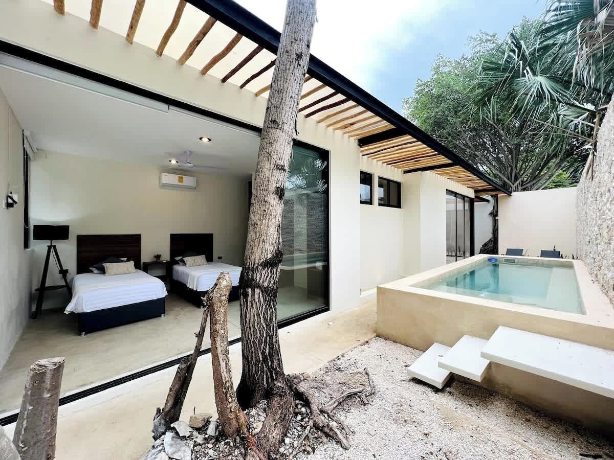 A modern bedroom with two beds, a large window, and a hot tub.